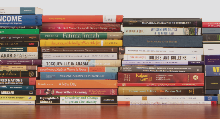 Four stacks of books on a shelf. The spines of the books are facing toward the viewer.