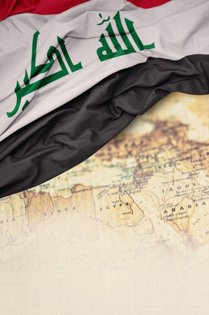 The Iraqi flag draped over a partially visible vintage map, with the flags red, white, black, and green Arabic script clearly shown at the top of the image.