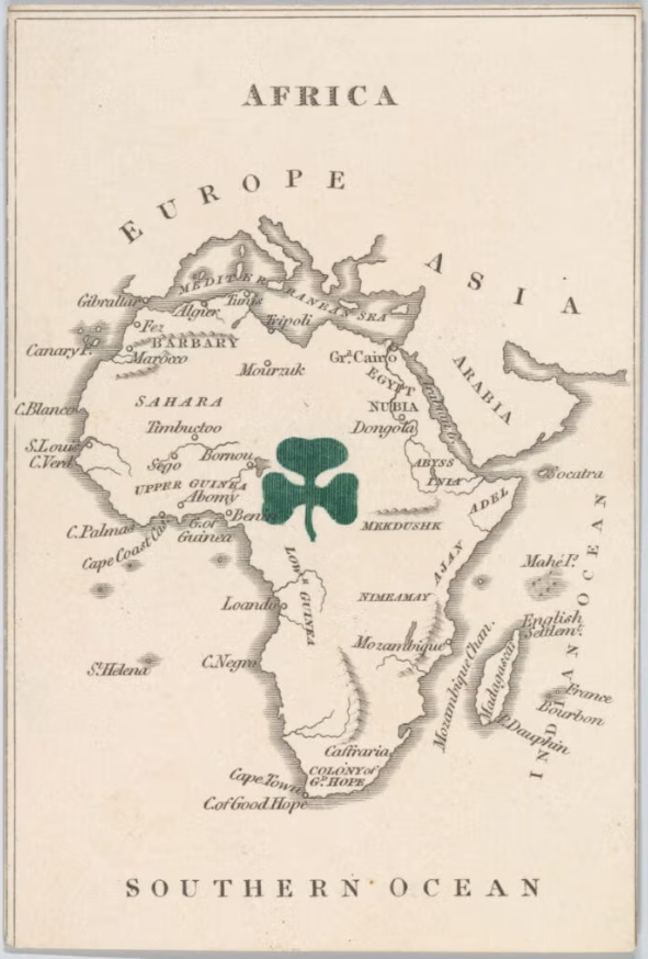 A vintage map of Africa labeled with surrounding continents and major regions. A large green shamrock symbol is centered over the continent.