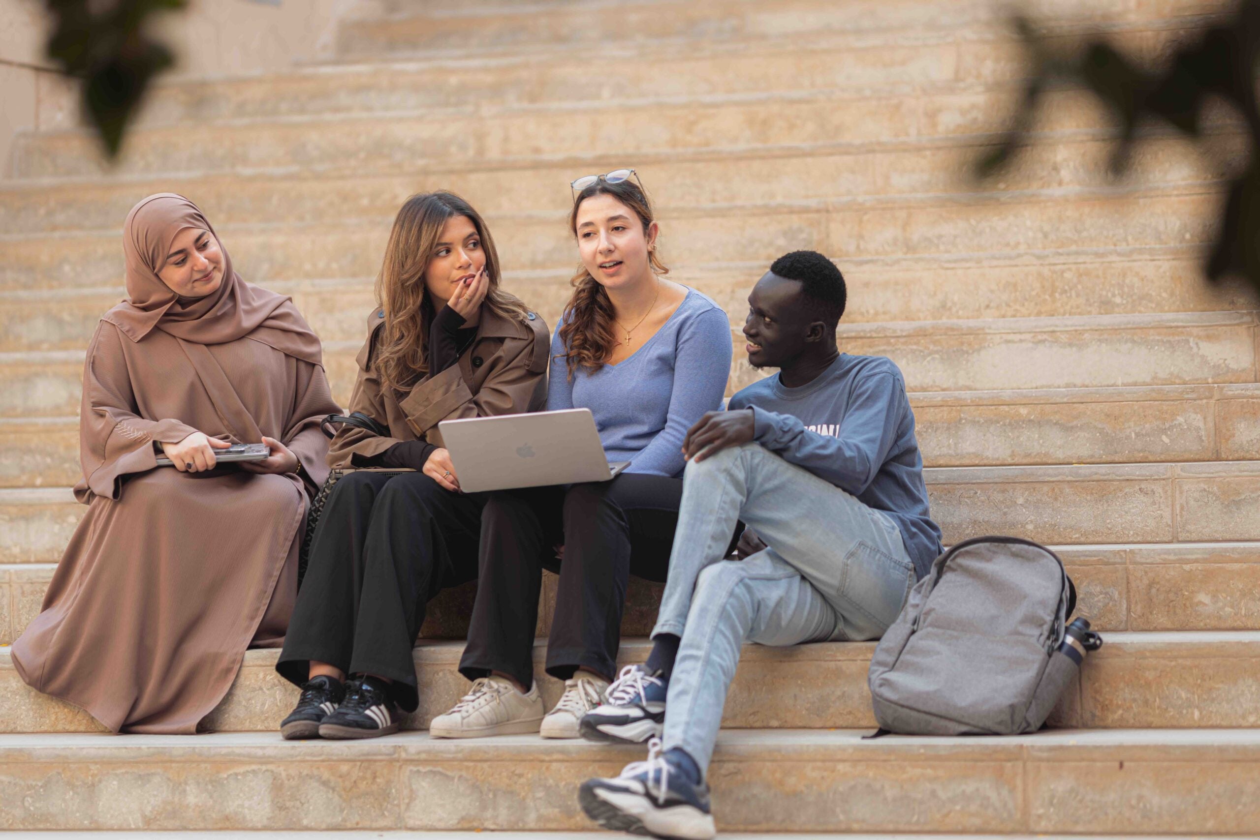 Students sitting on stairs with one holding a laptop