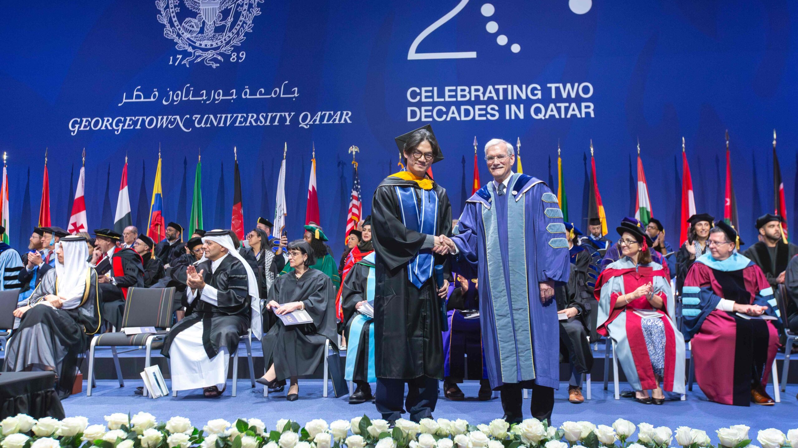 Brian Wibowo shakes hand of Interim President Groves at 2025 Commencement ceremony