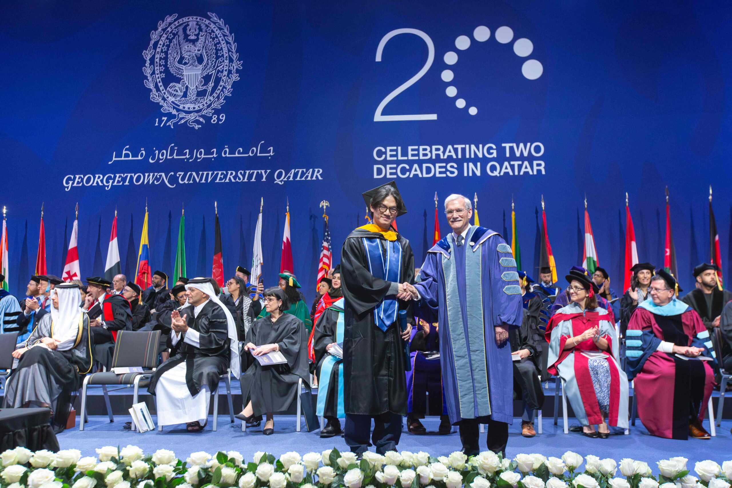 Brian Wibowo shakes hand of Interim President Groves at 2025 Commencement ceremony
