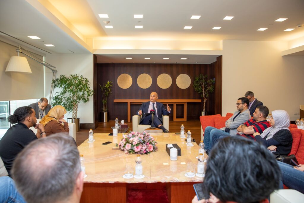 Dean Masri sitting in the room with different media outlet journalists